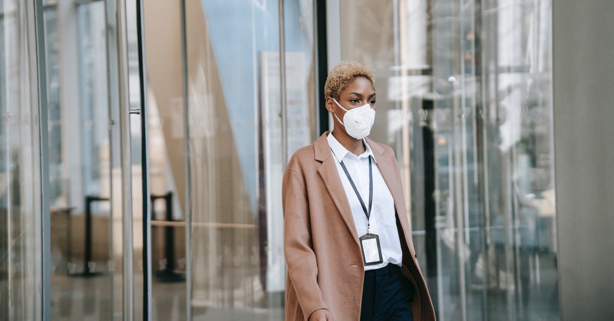 1.9 Executing as AreaEffectClouds - Serious black businesswoman in mask walking along glass building