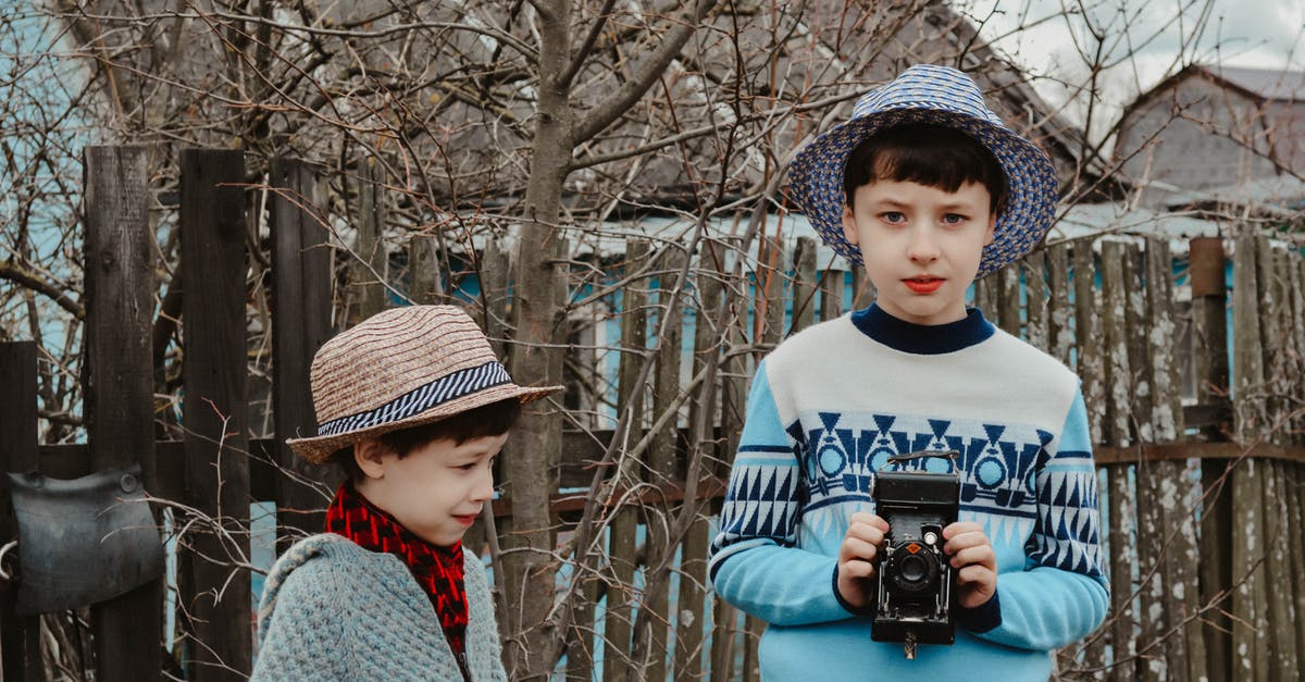 A villager asked me to take a picture and send it to them. How do I do that? - Focused preteen boy in warm sweater and straw hat standing near wooden fence together with little brother and taking photo on vintage camera A villager asked me to take a picture and send it to them. How do I do that? - Focused preteen boy in warm sweater and straw hat standing near wooden fence together with little brother and taking photo on vintage camera