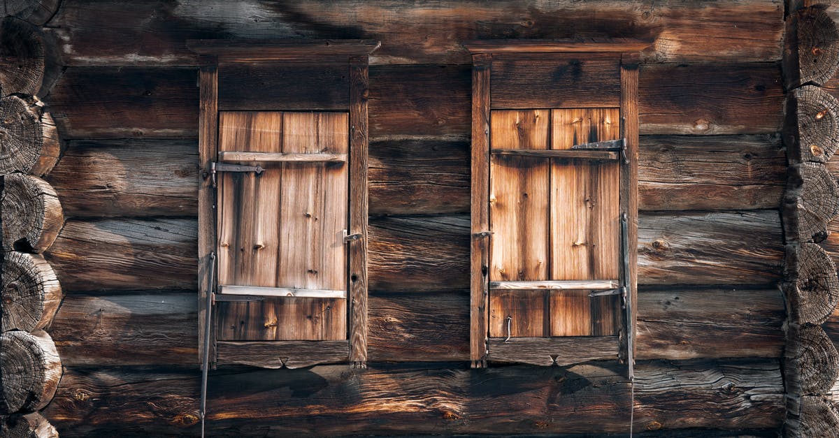 Abandoned village to Village - Detail of exterior of shabby rustic house made of wooden logs with closed windows on sunny day