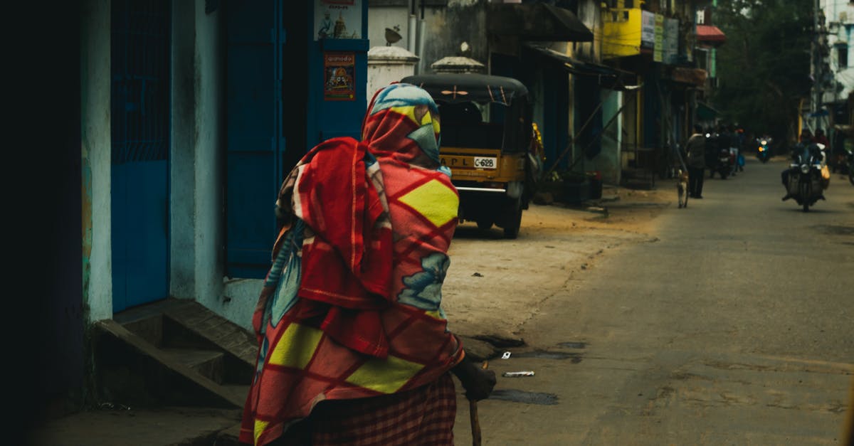 Accedently substituted my clash of clans village with a new one while trying to connect. How do i get my old village back? - Back view of unrecognizable ethnic indigenous person in rustic colorful clothes with hand stick walking on old shabby street in residential district