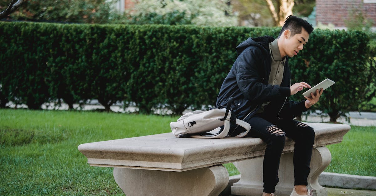Accessing biome-specific grass tints w/out use of external programs? - Full body of young focused Asian male in casual wear sitting on bench in park and browsing internet on tablet