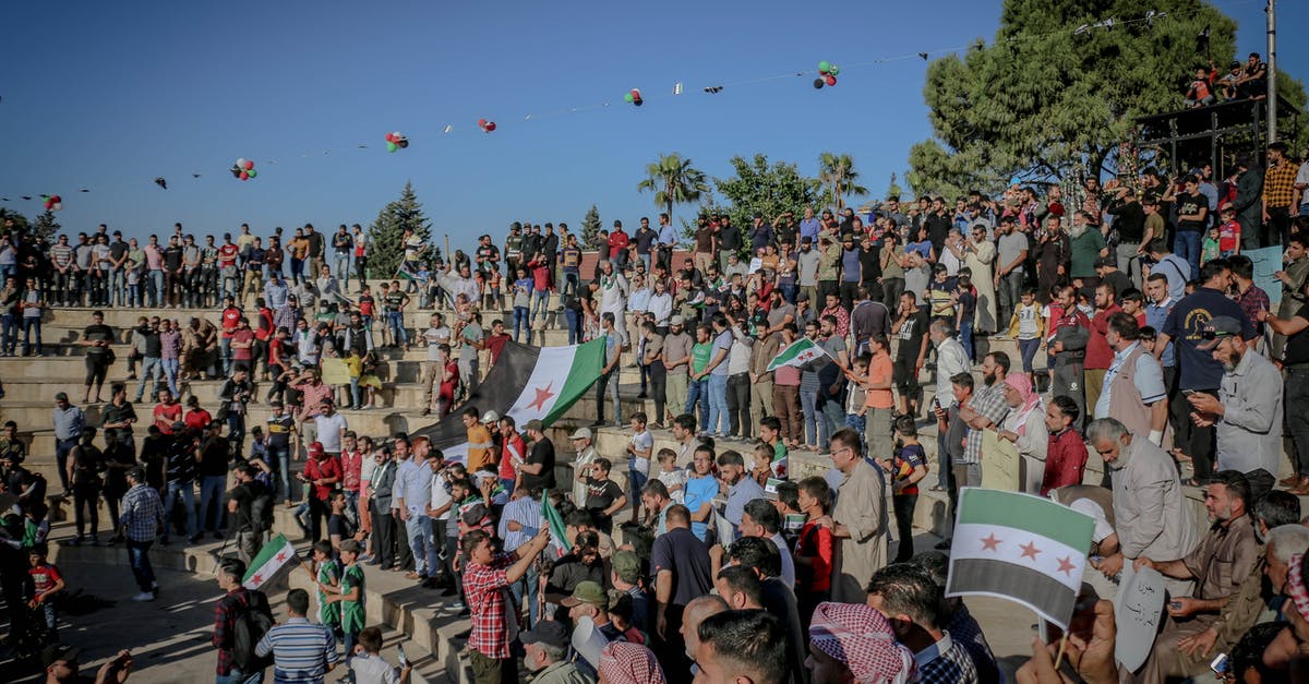 Activating godmode in Super Star Wars for SNES? - Crowd of anonymous Arab activists with Syrian flags on urban stairs during rally under blue sky