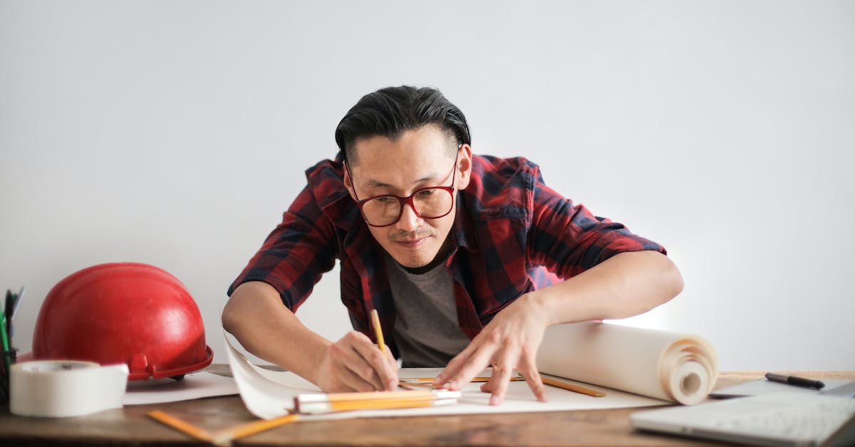 After clearing cache/storage, won't let us create a new profile - Inspired young male engineer in glasses drawing draft on paper bending over table against white wall