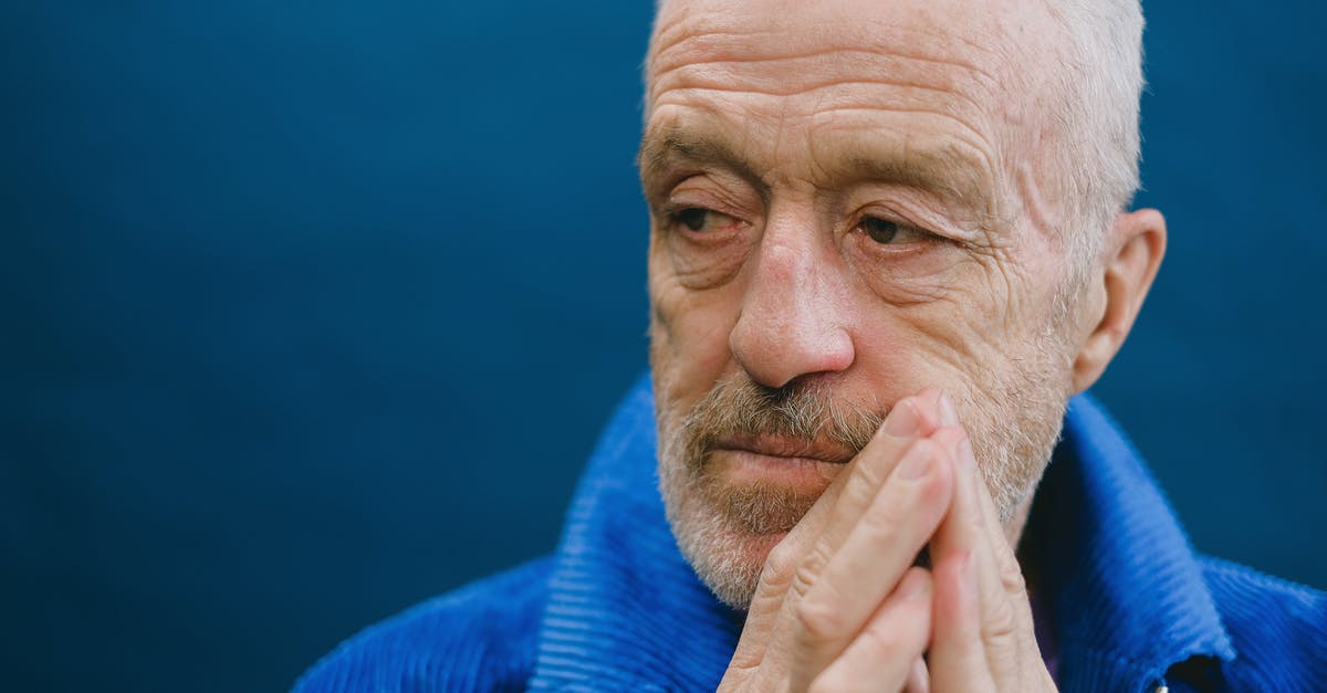 Age of Decadence how to kill guy in training? - Portrait of elderly bearded gray haired male in blue jacket standing against dark blue background putting hands together in front of face and looking away Age of Decadence how to kill guy in training? - Portrait of elderly bearded gray haired male in blue jacket standing against dark blue background putting hands together in front of face and looking away