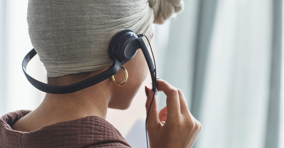 Agent A: Lightbulb and a Hammer - Back view of crop anonymous female call agent with microphone in turban standing in light room during work at home Agent A: Lightbulb and a Hammer - Back view of crop anonymous female call agent with microphone in turban standing in light room during work at home