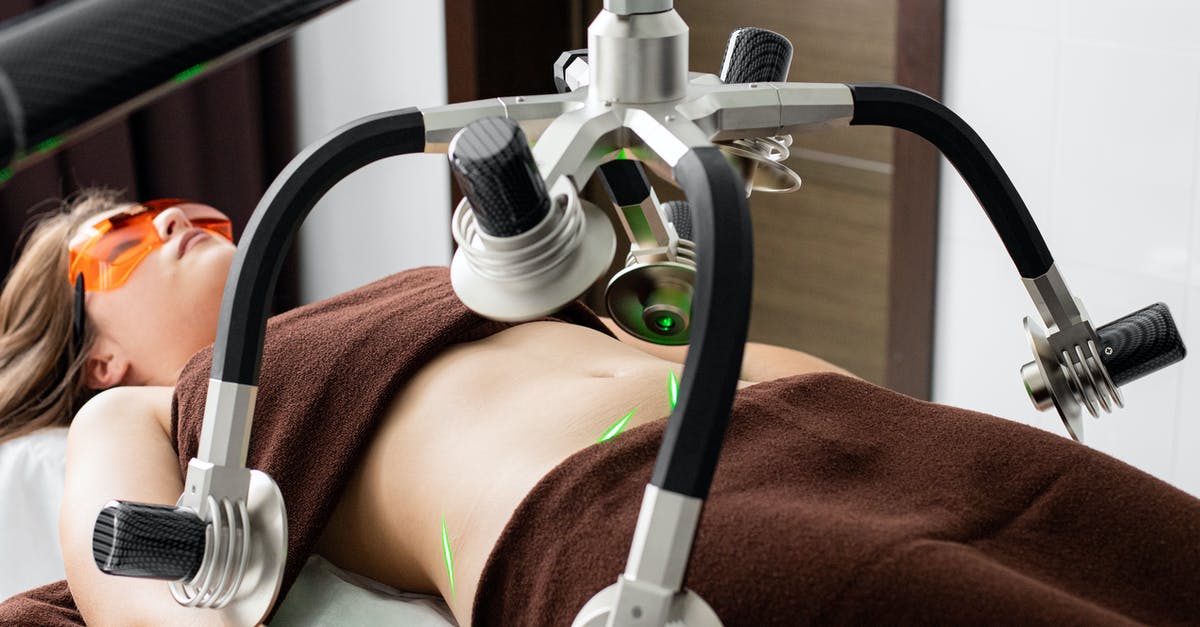 Amperage for Fat PS2 with IEC C13 Female Lead Plug To UK 3 Pin Plug? - Female client lying on table under lasers of modern weight loss machine on belly during liposuction procedure in medical clinic