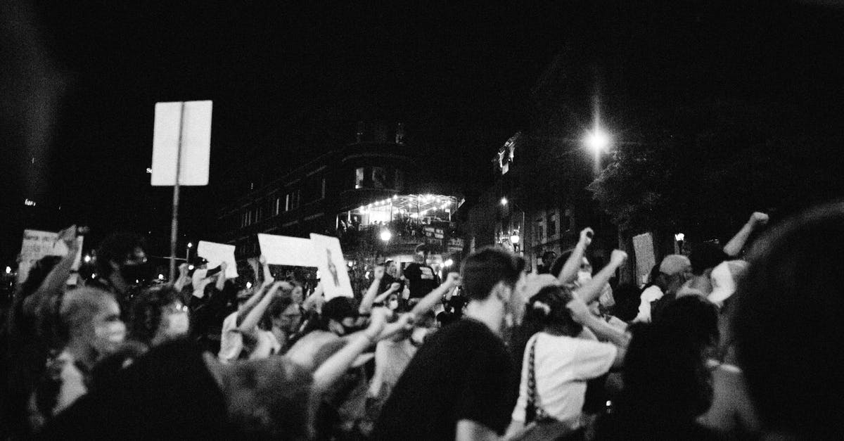 Angry Wolves on Demand! - Side view of black and white anonymous aggressive demonstrators with fists up during protest on street at night