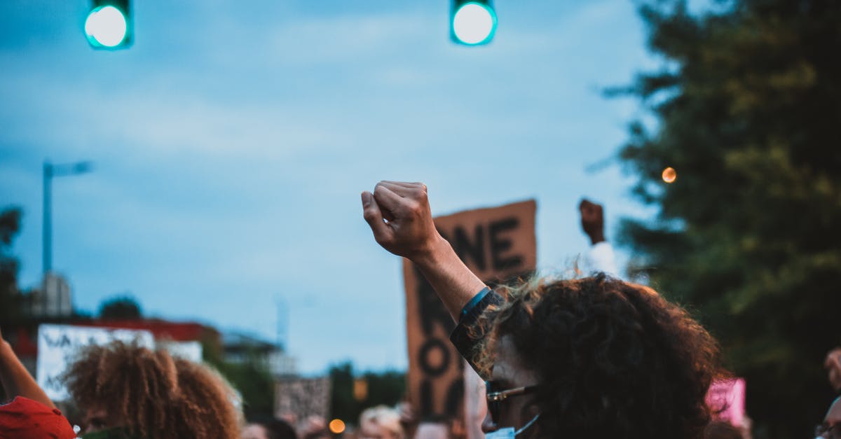 Angry Wolves on Demand! - Unrecognizable man with fist up during demonstration in evening