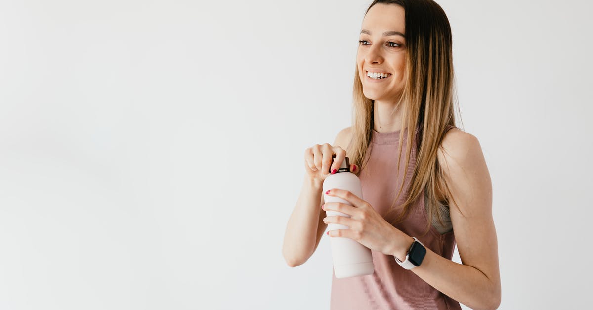 Are lunchbox contents determined at time of opening? - Happy young woman opening cosmetic bottle while standing against white background