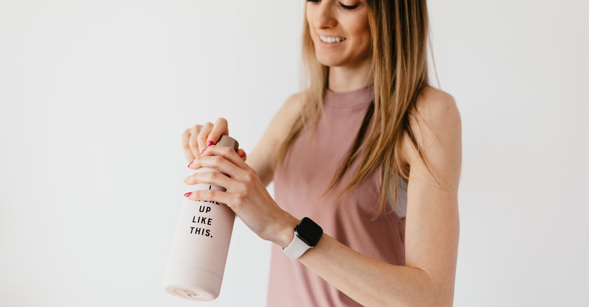 Are lunchbox contents determined at time of opening? - Crop cheerful young female in casual clothes with smart watch on wrist opening bottle on white background Are lunchbox contents determined at time of opening? - Crop cheerful young female in casual clothes with smart watch on wrist opening bottle on white background