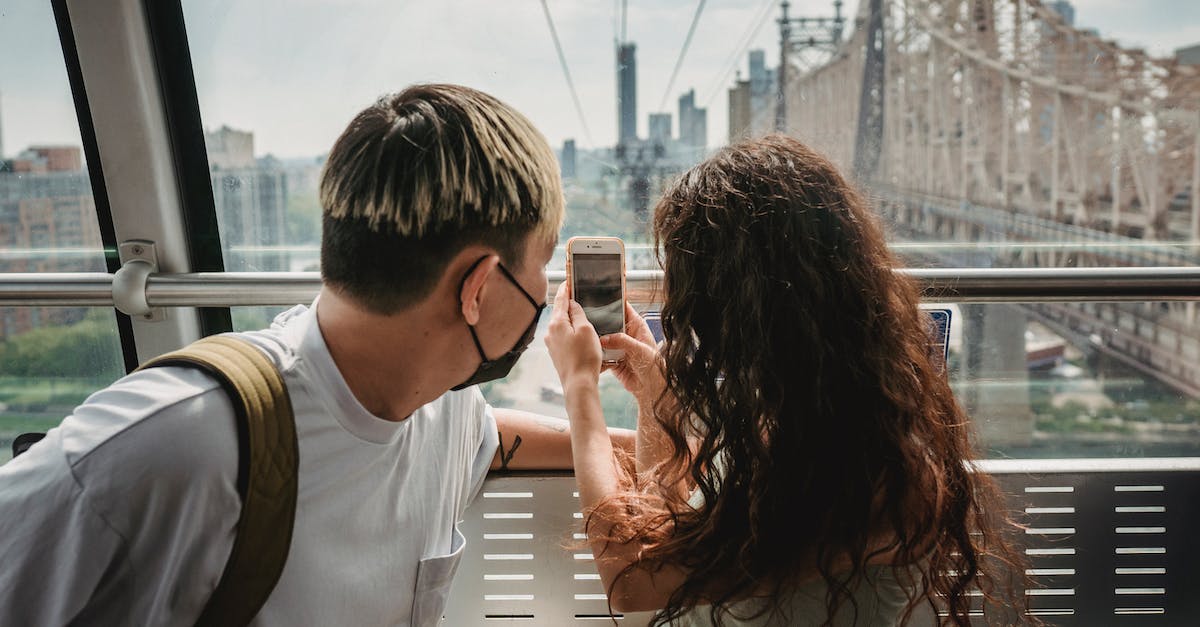 Are Memory Crystals new? - Young couple in protective mask taking photo on smartphone while riding together on cableway during vacation