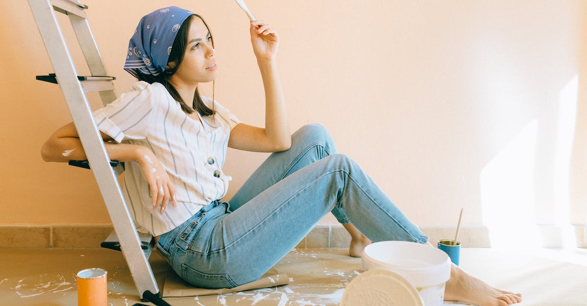 Are paint buckets removed permanently after use? - Woman Sitting on the Floor Holding a White Paintbrush