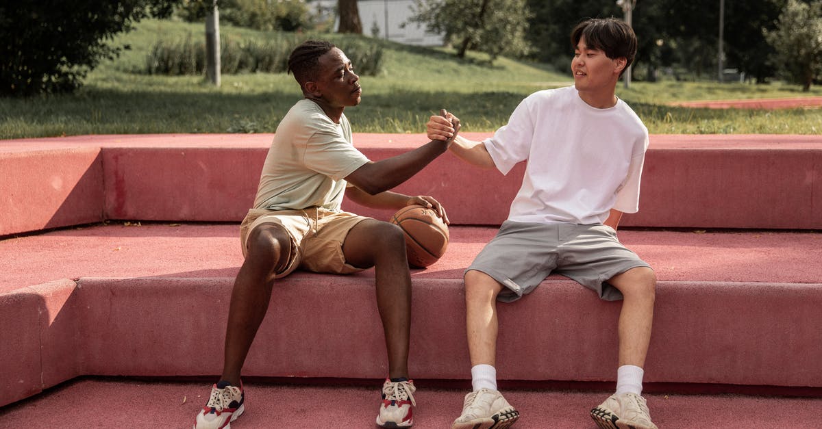 Are the contents of the overheard conversation at the beginning of the game ever resolved? - Full length of sporty young diverse male friends greeting each other while sitting on bench in park after playing streetball