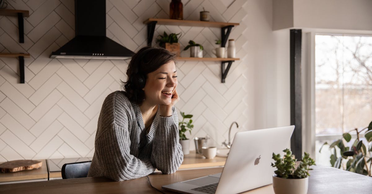 Are the free online packs able to be reaquired on consecutive playthroughs? - Young cheerful female smiling and talking via laptop while sitting at wooden table in cozy kitchen