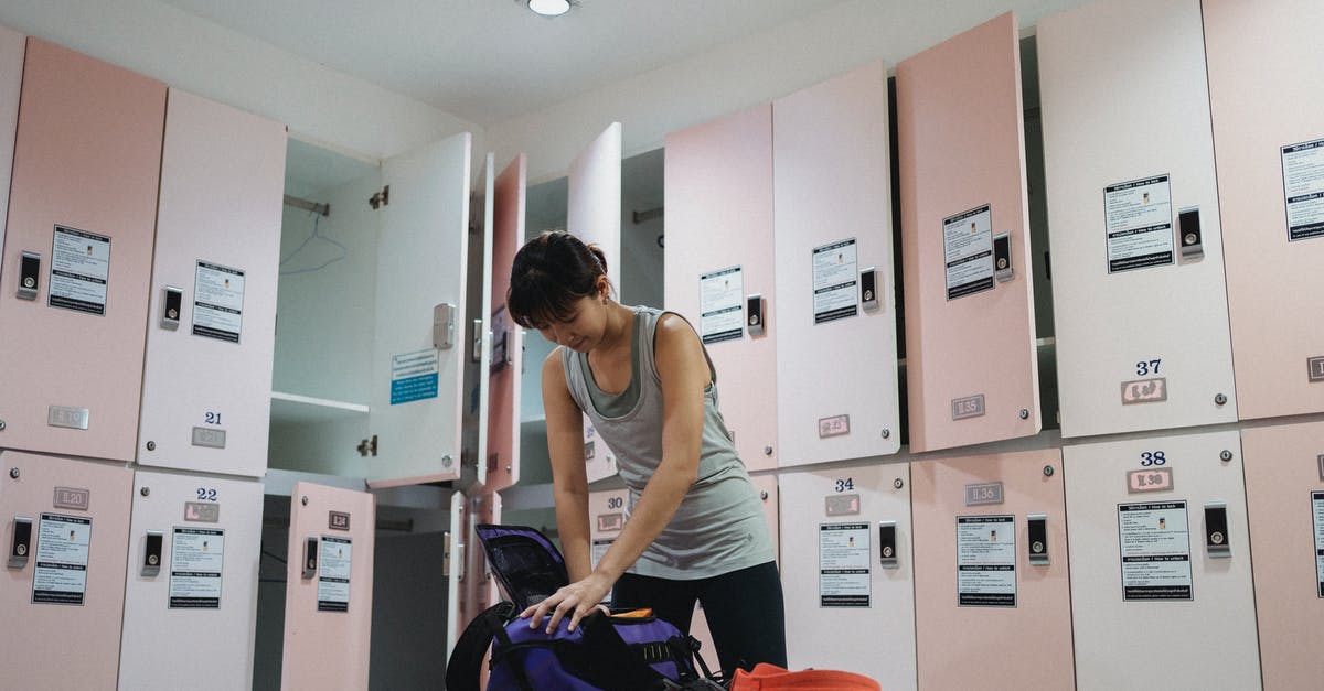 Are the locked containers in the Cisten Training Room safe? - Low angle of slim concentrated female athlete preparing footwear and safety equipment while standing alone in contemporary locker room