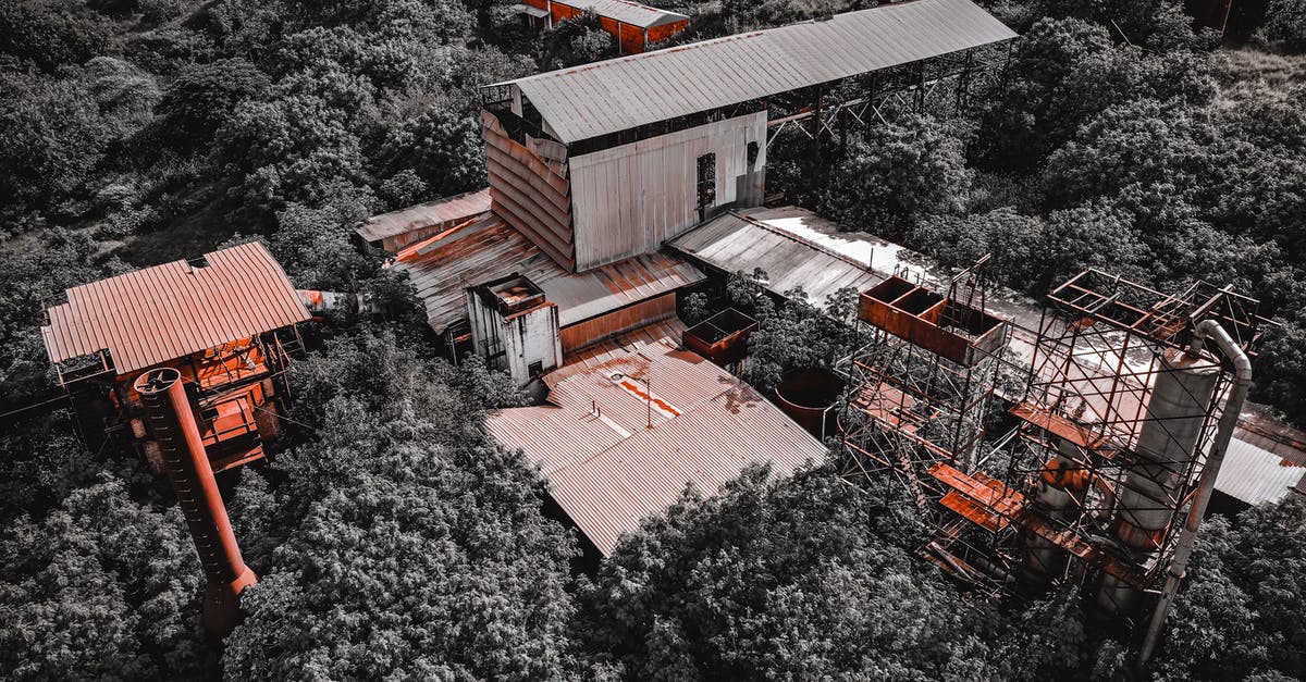 Are there any downsides to having a coal deficiency if you've only used coal to build factories? - Drone view of aged abandoned coal mine with shabby buildings with red and gray roofs located in thick forest in summertime