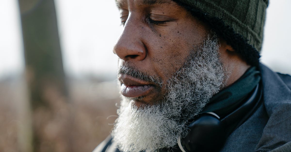 Are there any silenced energy weapons availiable? - Closeup of bearded concentrated African American male with headphones on neck meditating with closed eyes
