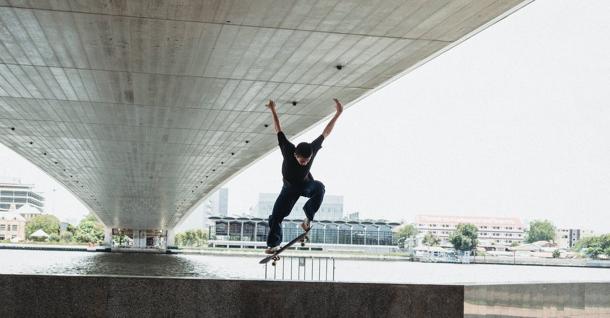 Are there any stunt jumps IN the water? - Millennial man doing trick with skateboard on waterfront