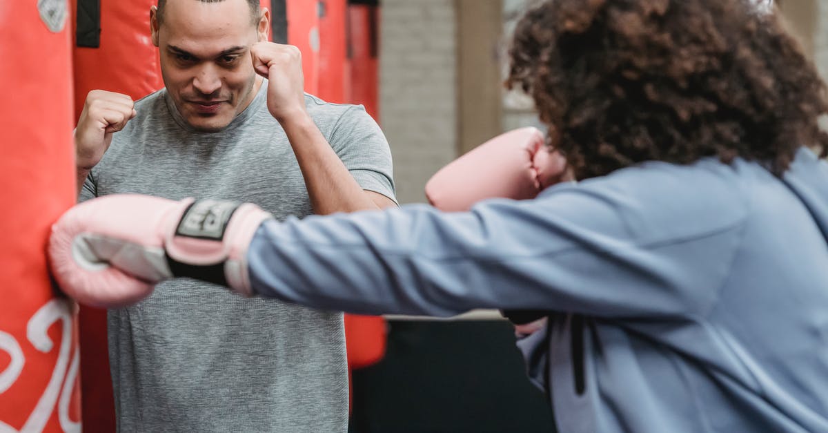 Are there critical hit attacks? - Serious ethnic male instructor showing boxing stance to female in gloves hitting punching bag during workout