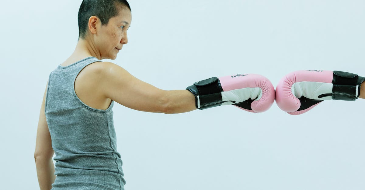 Armor stand for punching in Minecraft - Side view of confident mature ethnic female boxer wearing sportswear and pink boxing gloves while giving fist bump on white background in light studio Armor stand for punching in Minecraft - Side view of confident mature ethnic female boxer wearing sportswear and pink boxing gloves while giving fist bump on white background in light studio