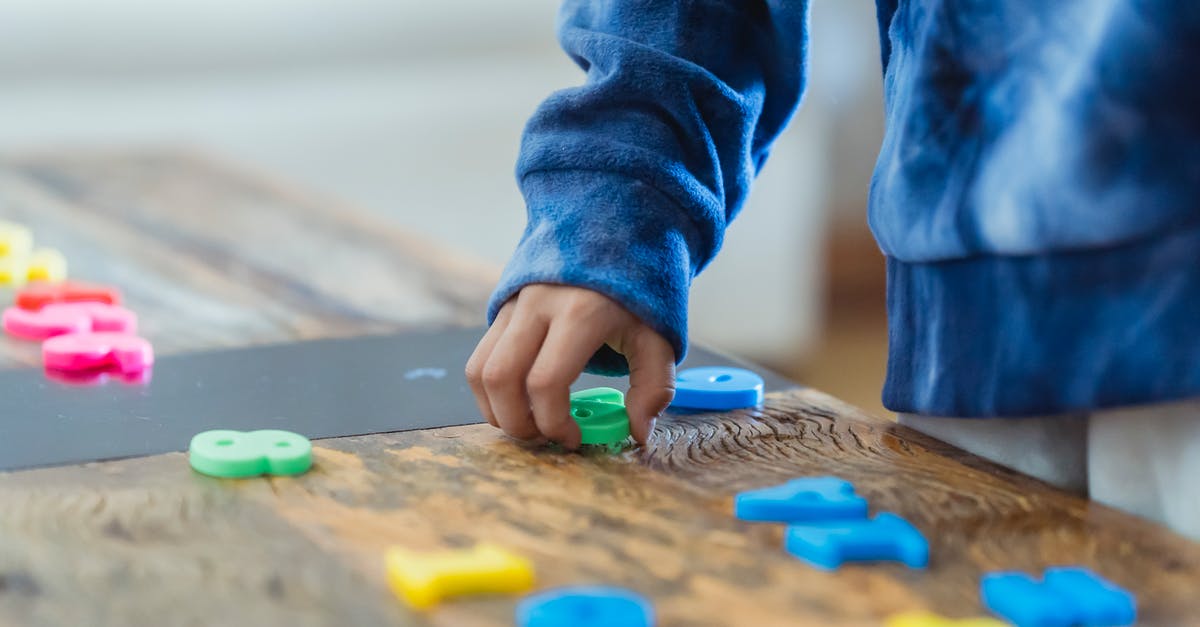 At which point does a game count towards my stats? - Crop anonymous ethnic boy taking plastic number from wooden table while learning math