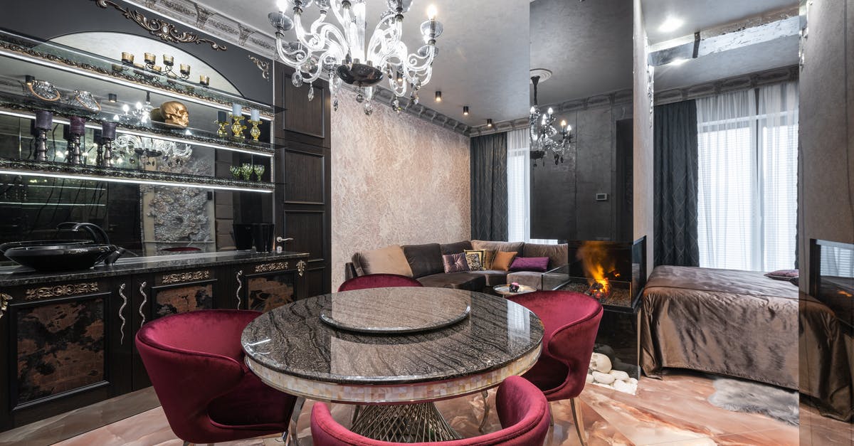 Avatar of Fire and Elemental Equlibrium - Armchairs at table placed near kitchen counter with kitchenware in modern spacious apartment with bed near burning fireplace and couch