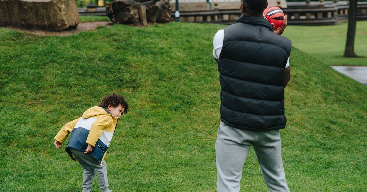 Ball curves on straight throw - Unrecognizable black father playing with kid