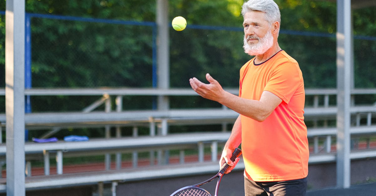Ball curves on straight throw - Focused elderly man playing tennis on street Ball curves on straight throw - Focused elderly man playing tennis on street
