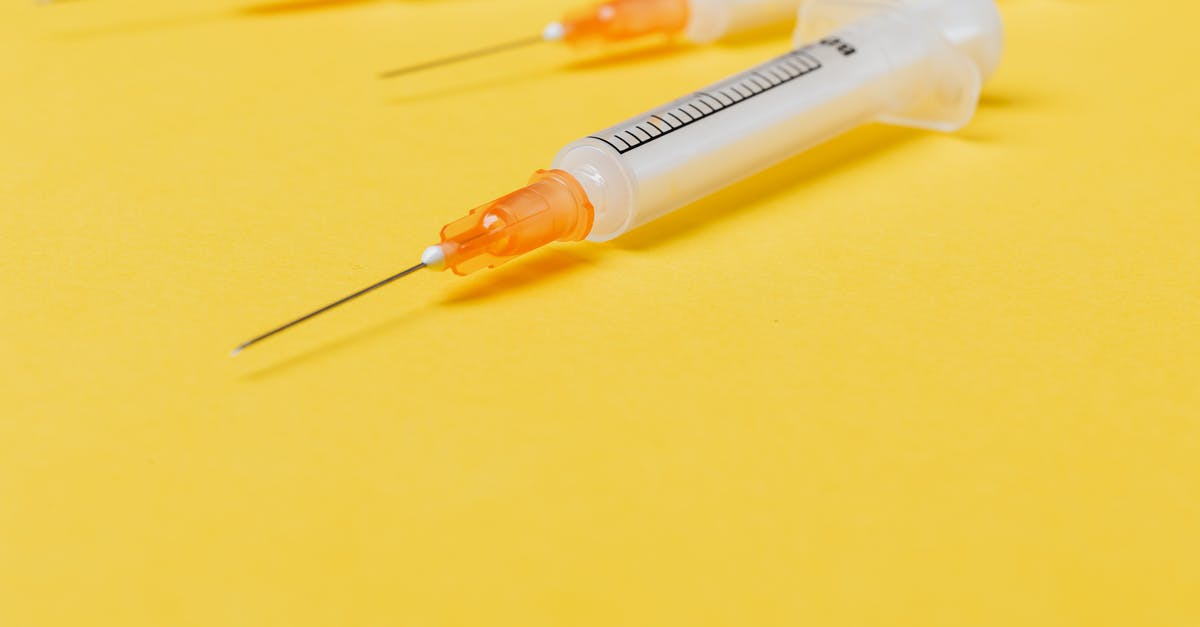 Barrel used as stash is no longer neutral - Medical single use disposable syringe without protective cover on needle and with empty barrel placed on bright yellow surface