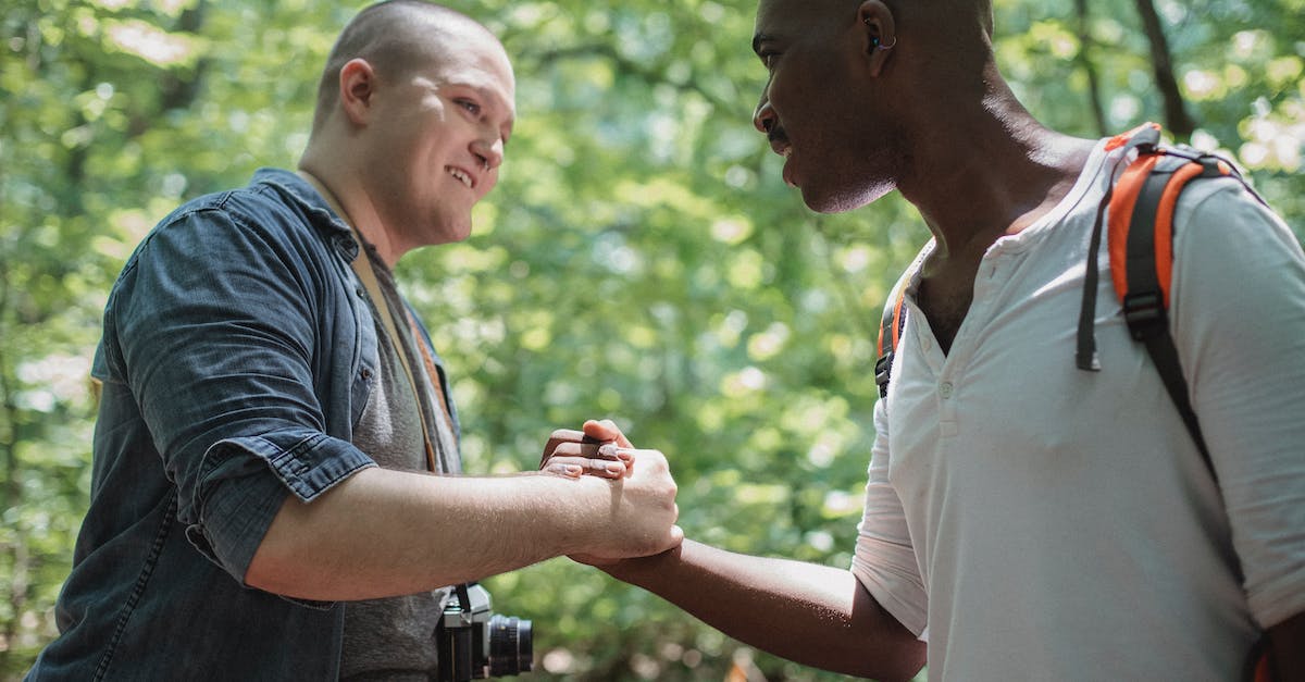 Battlefront: Is there a specific number of units active for each side? - Side view cheerful diverse male friends in casual clothes shaking hands and looking at each other while trekking together in green forest