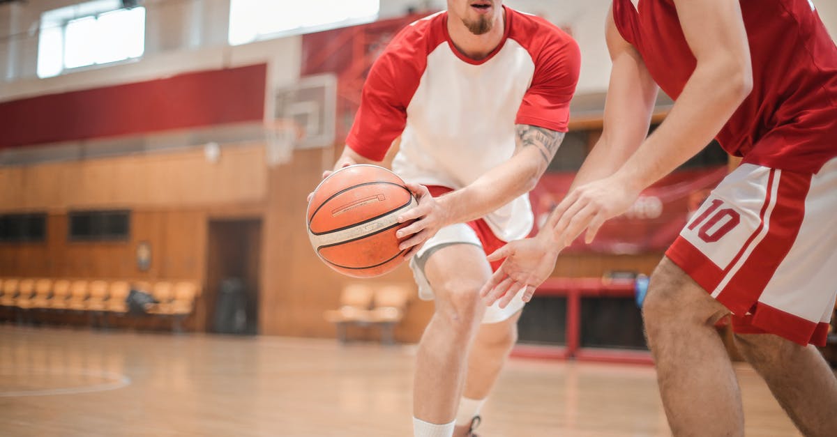 Battling at a gym simultaneously with other players - Man in Red and White Nike Crew Neck T-shirt and White Shorts Holding Basketball