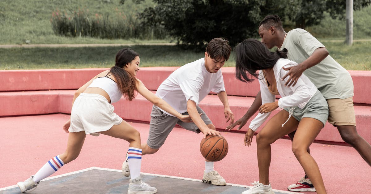 Best move when they are no more certain moves left - Side view group of active young multiracial friends in in casual outfits and sneakers playing basketball on sports ground in green park