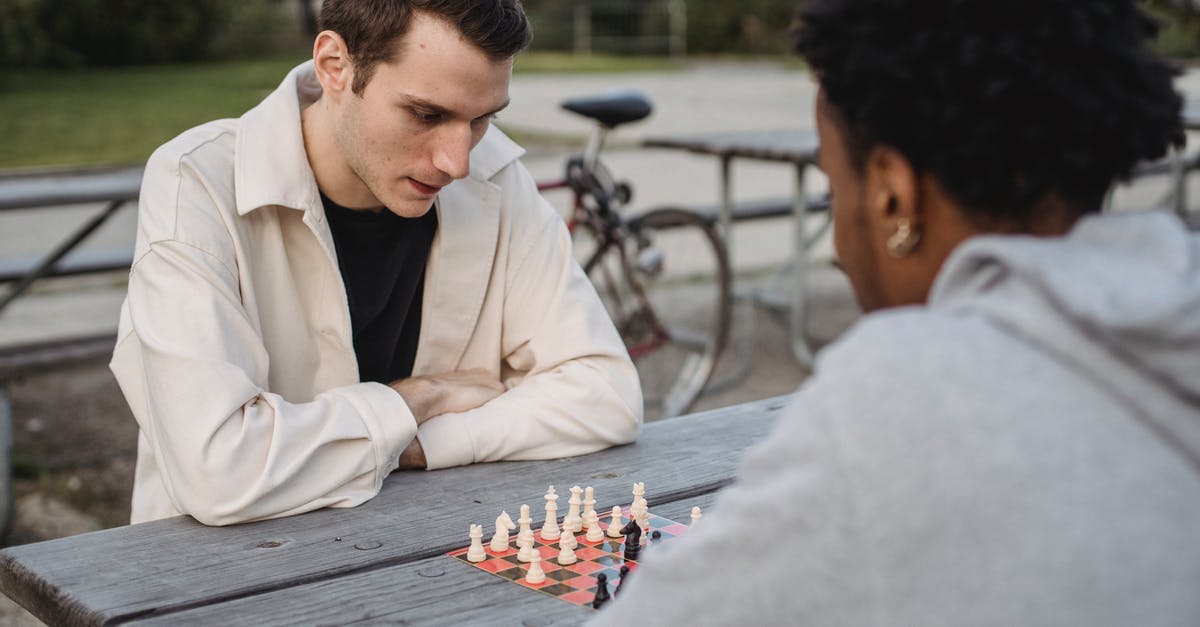 Best strategy for defending last Institute mission - Concentrated young guy in casual clothes thinking while playing chess game with anonymous African American male friend in park Best strategy for defending last Institute mission - Concentrated young guy in casual clothes thinking while playing chess game with anonymous African American male friend in park