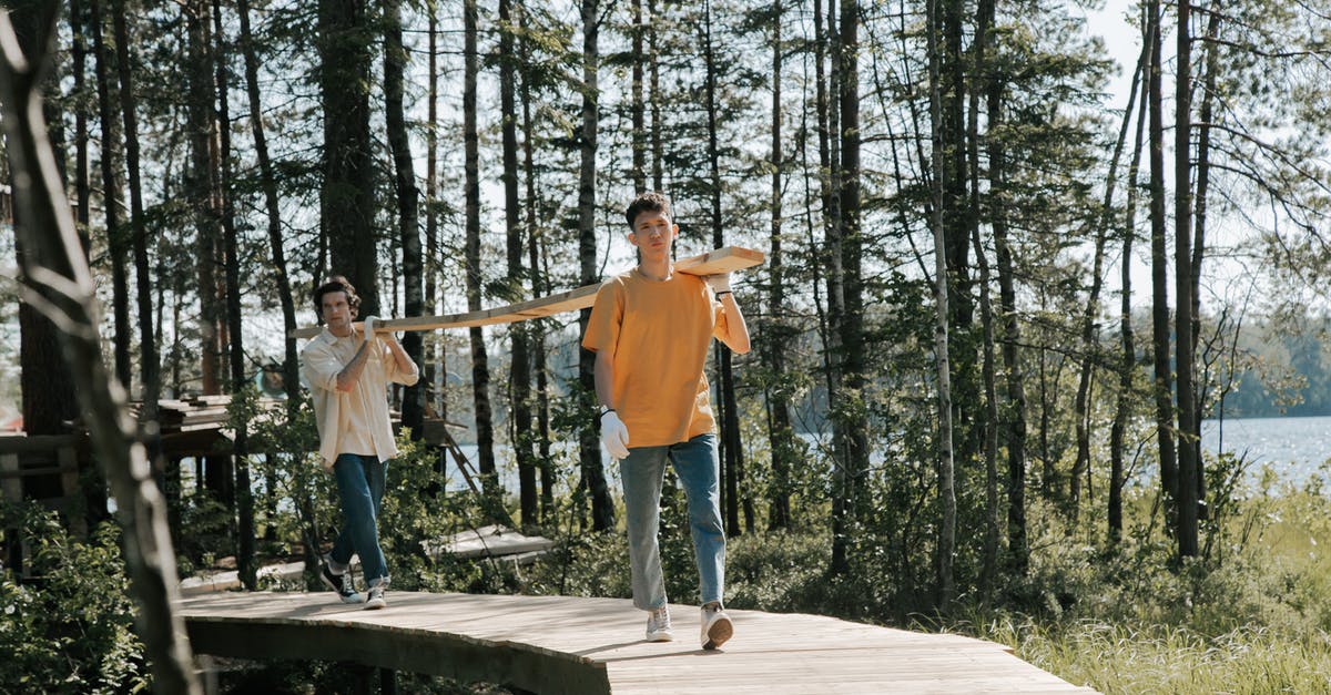 Bioshock; walking problem? - Man in Orange T-shirt and Blue Denim Jeans Standing on Brown Wooden Bridge Bioshock; walking problem? - Man in Orange T-shirt and Blue Denim Jeans Standing on Brown Wooden Bridge