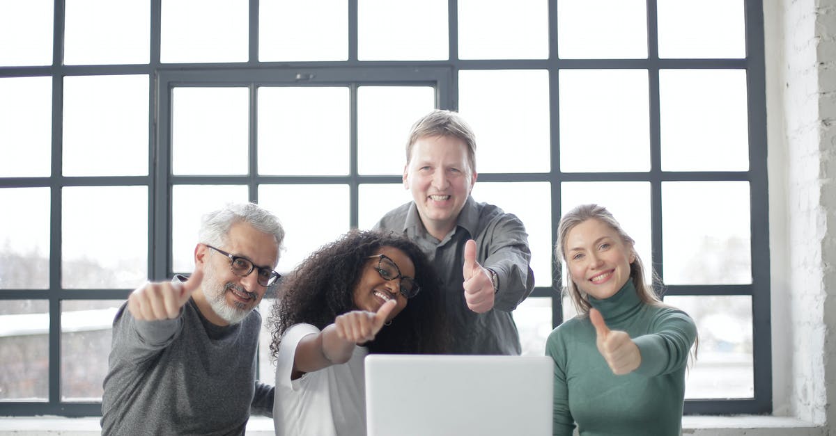 Black ops 2 dlcs download and install but doesn't show up - Happy multiracial team sitting at table with laptop and working on successful project while demonstrating thumb up gesture and smiling at camera