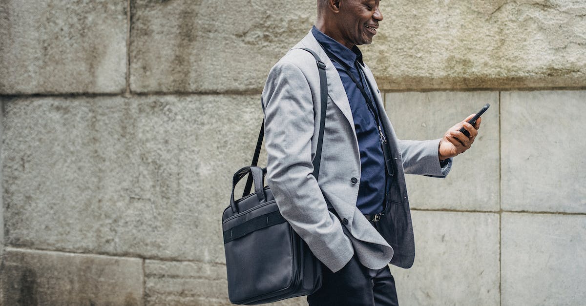 Blocks that look quartz - Cheerful black manager looking at smartphone while walking down street
