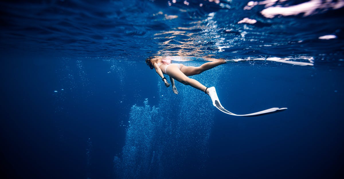 Blue checkmark under player's name in scoreboard - Female diver in swimwear and flippers swimming on surface of deep blue ocean Blue checkmark under player's name in scoreboard - Female diver in swimwear and flippers swimming on surface of deep blue ocean