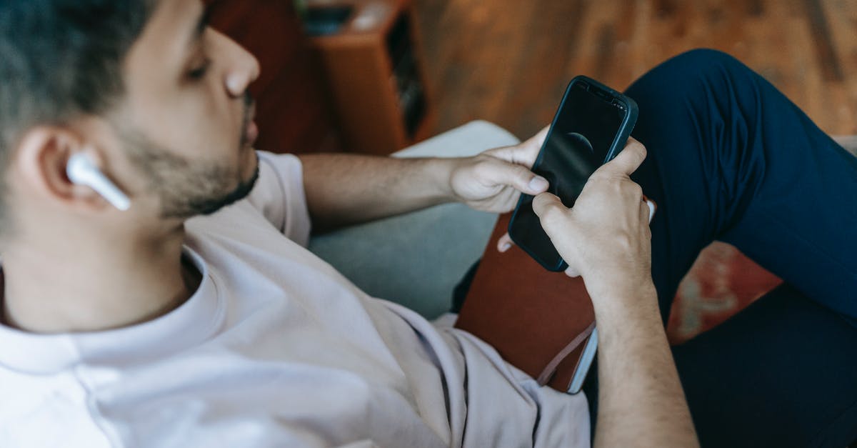 Bluetooth Audio with Playstation TV - Indian man surfing smartphone while listening to music Bluetooth Audio with Playstation TV - Indian man surfing smartphone while listening to music