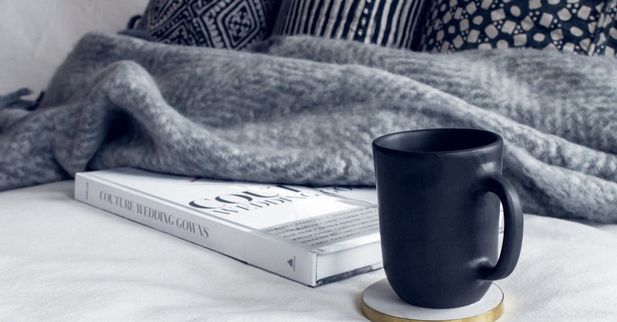 Book found inside baneswood - Black Ceramic Mug on Round White and Beige Coaster on White Textile Beside Book