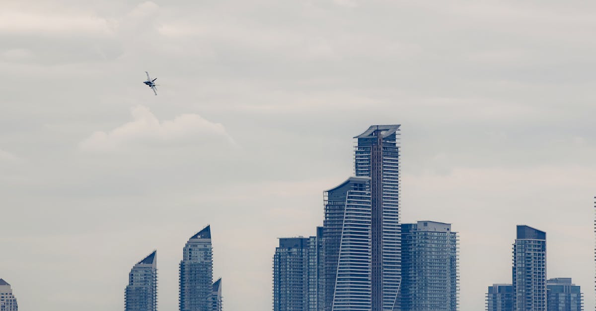 Build a plane or rocket for Kerbal high altitudes - Military airplane flying above modern skyscrapers in city