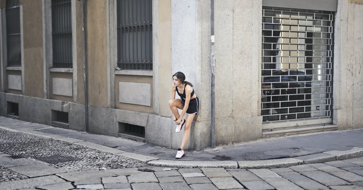 Building utilities on a wall corner - Sportswoman tying shoelaces during training in city