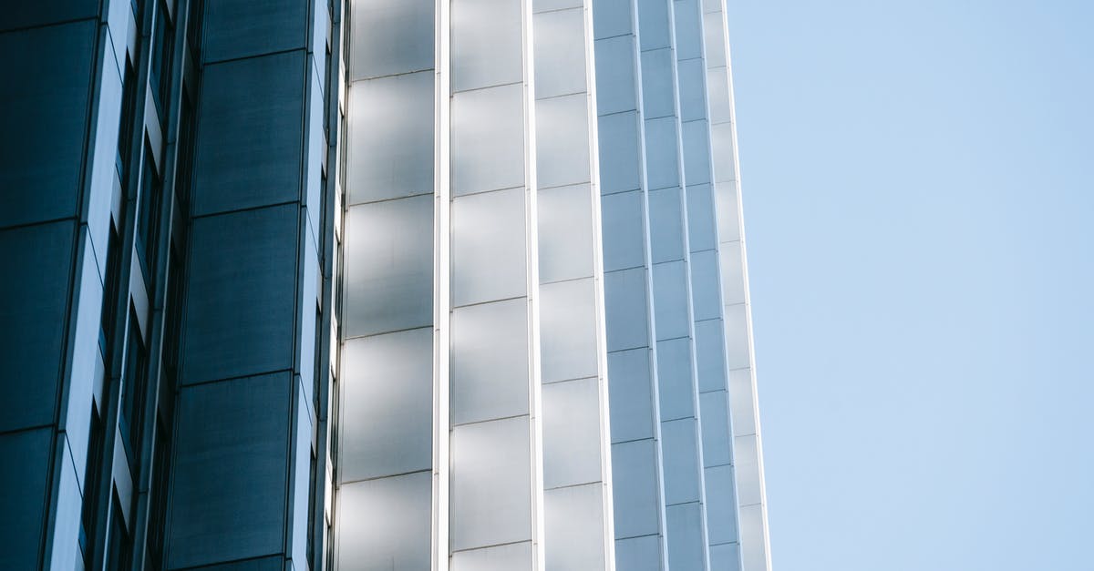 Building utilities on a wall corner - Low angle exterior design of contemporary multistory urban building with geometric shapes and gray panels against blue sky
