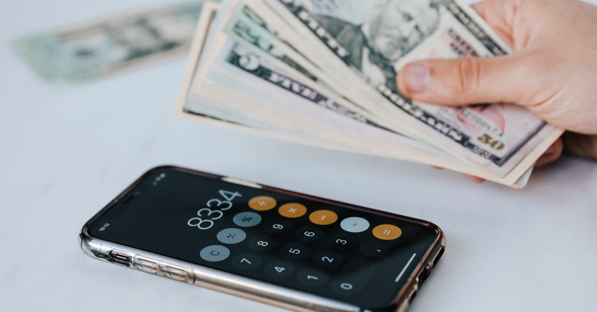 Caesar 3 - Why don't I get any tax money from my senate? - Calculator application on mobile phone screen on white surface near crop anonymous person holding pile of dollars