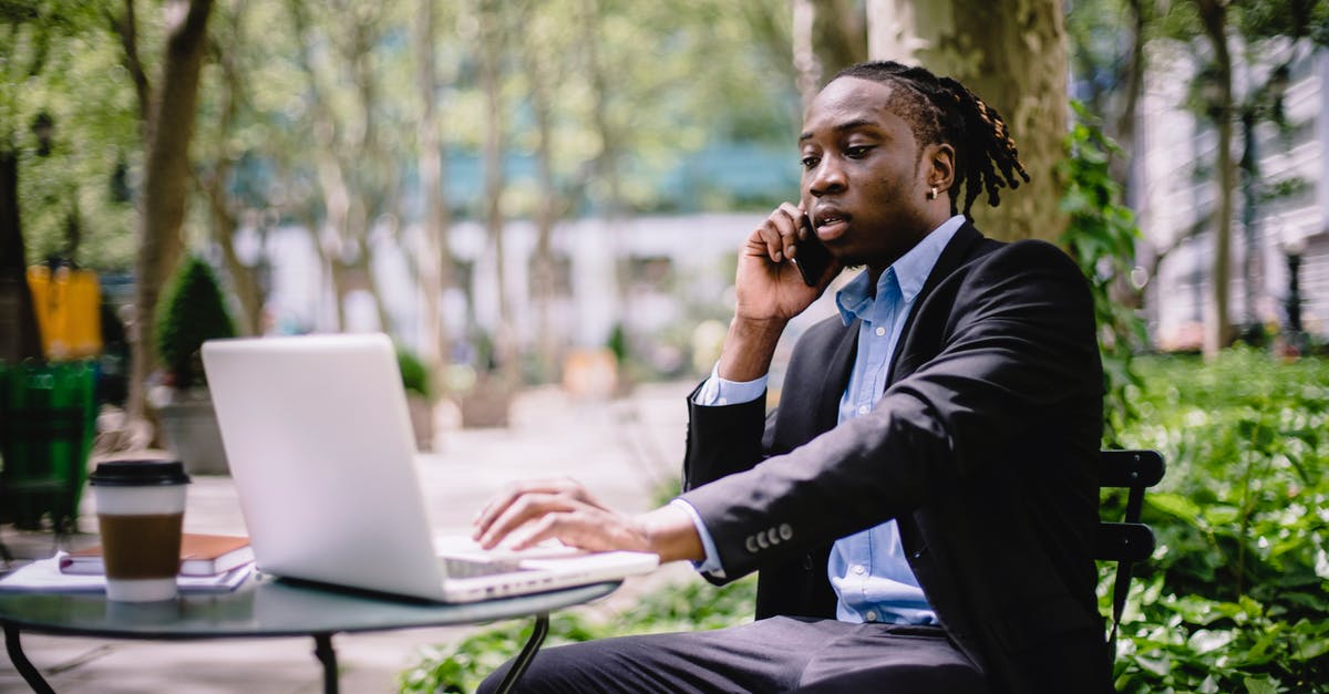 Call of duty Black ops - not responding - Serious stylish young African American male manager in formal wear browsing laptop while having phone call in outdoor cafe Call of duty Black ops - not responding - Serious stylish young African American male manager in formal wear browsing laptop while having phone call in outdoor cafe