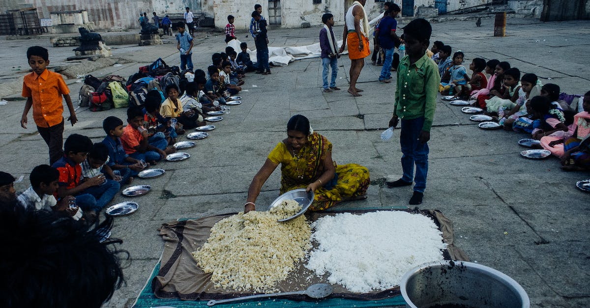 Can't access Reef Social area [duplicate] - From above of old Indian woman serving food on plates while sitting on ground surrounded with kids in poor area
