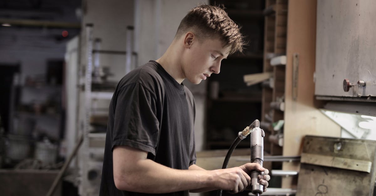 Can't assemble the pot, it keeps breaking - Side view of young male worker using pneumatic tool for handling detail in workshop Can't assemble the pot, it keeps breaking - Side view of young male worker using pneumatic tool for handling detail in workshop