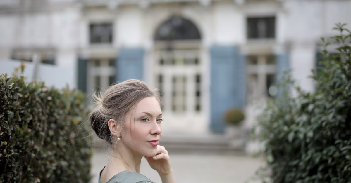 Can't finish building my house - Thoughtful casual lady in gray t shirt with beautiful hairstyle posing and looking away while standing near old building between trimmed bushes of garden Can't finish building my house - Thoughtful casual lady in gray t shirt with beautiful hairstyle posing and looking away while standing near old building between trimmed bushes of garden