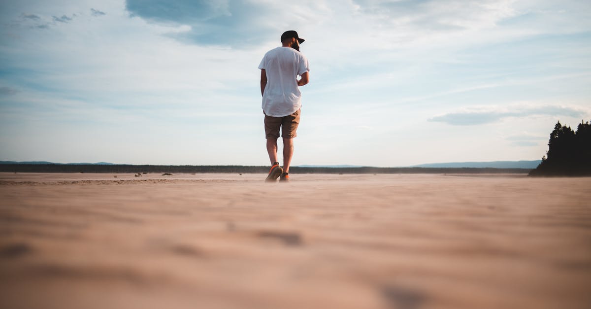 Can't get back from Sub Level 13 - Faceless hipster man walking on sandy shore under cloudy sky Can't get back from Sub Level 13 - Faceless hipster man walking on sandy shore under cloudy sky