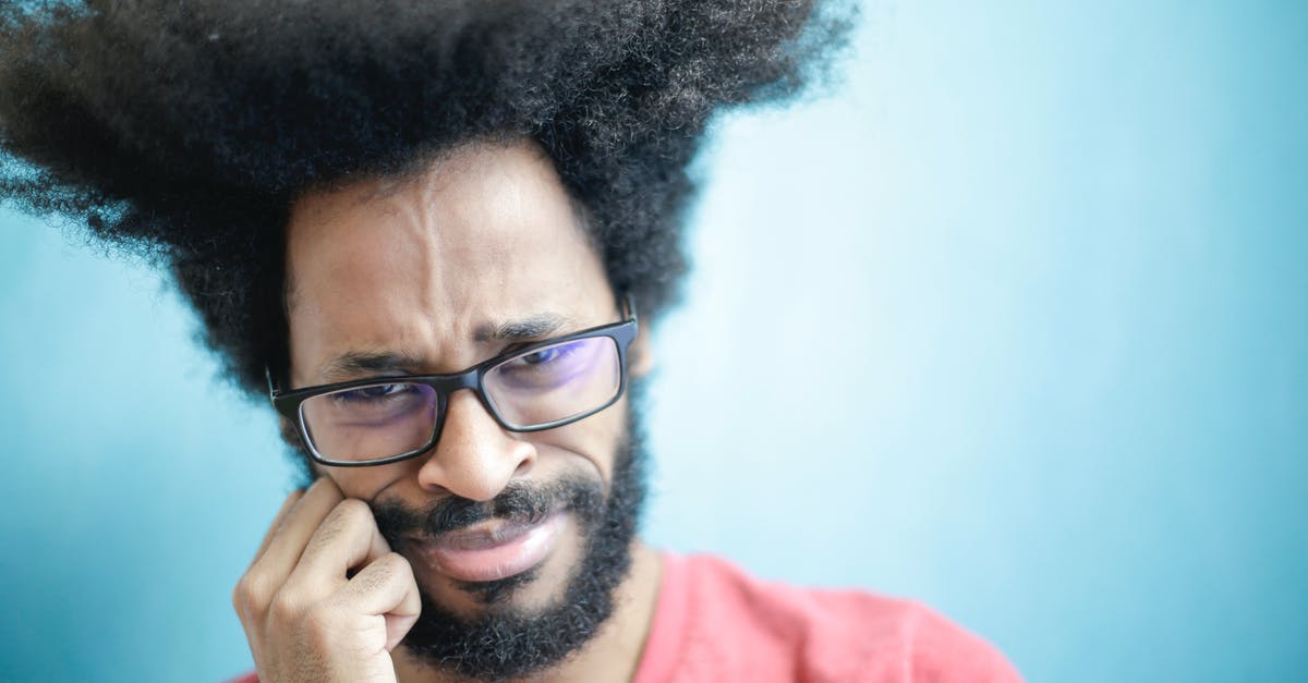 Can't get into 3rd puzzle - Suspicious young bearded ethnic male with creative Afro hairstyle wearing eyeglasses and pink t shirt touching cheek and looking at camera with uncertain or doubt expression Can't get into 3rd puzzle - Suspicious young bearded ethnic male with creative Afro hairstyle wearing eyeglasses and pink t shirt touching cheek and looking at camera with uncertain or doubt expression