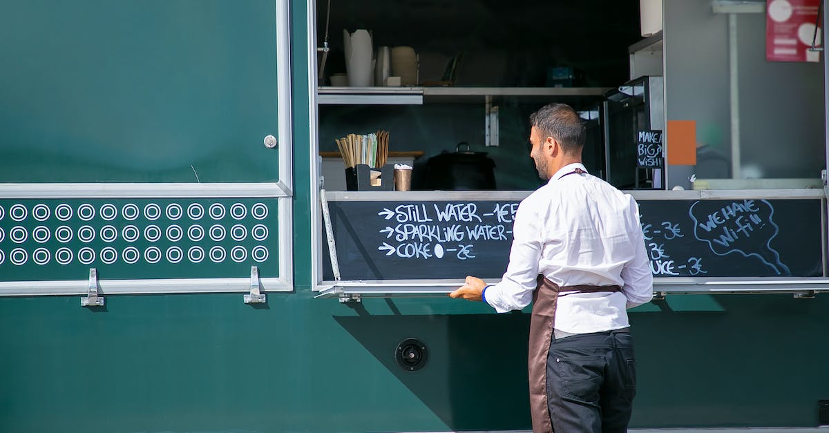 Can't open upgrades menu in MvM - Back view of male seller wearing apron preparing food truck with menu written on board